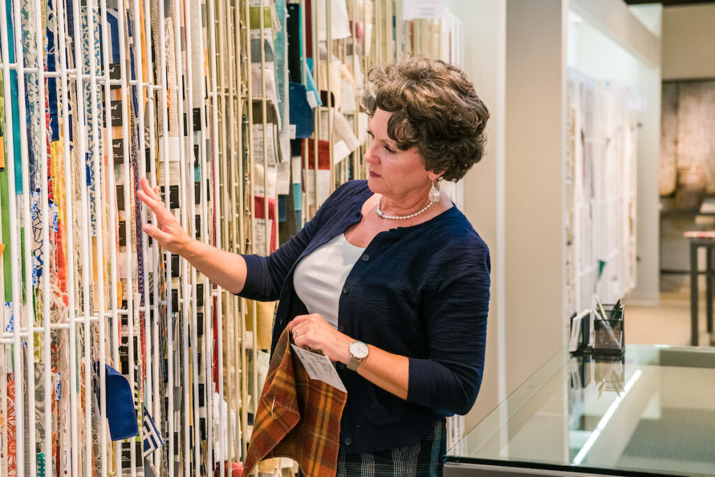 Michelle Ku, founder of Ku Interior Design, reviewing textile selections in a Denver design showroom